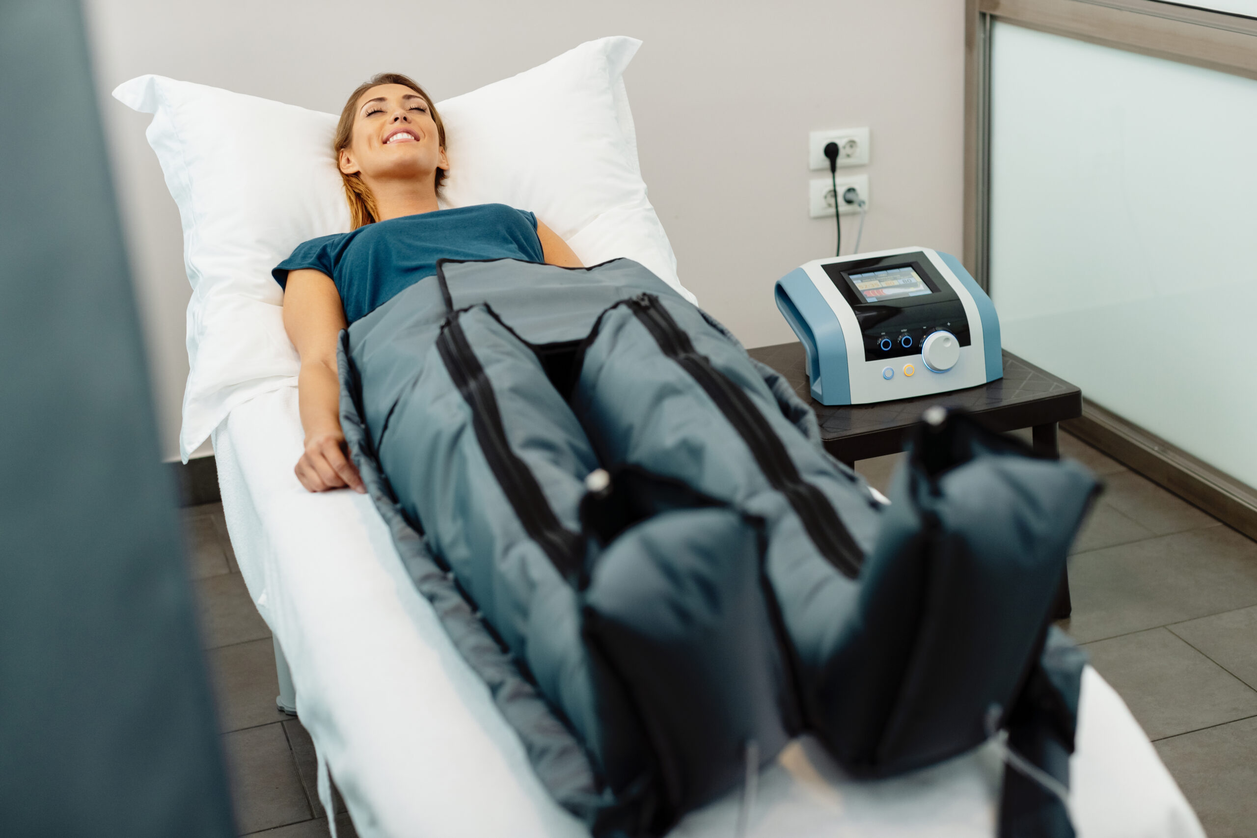 Young woman relaxing with eyes closed during pressotherapy at health spa.