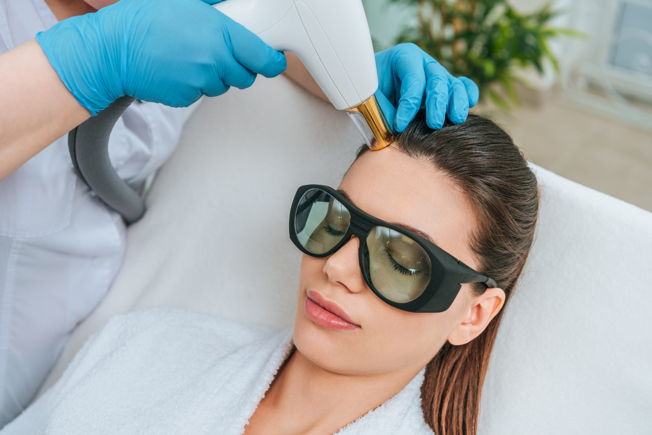 Relaxed woman in protective goggles receiving laser treatment in clinic